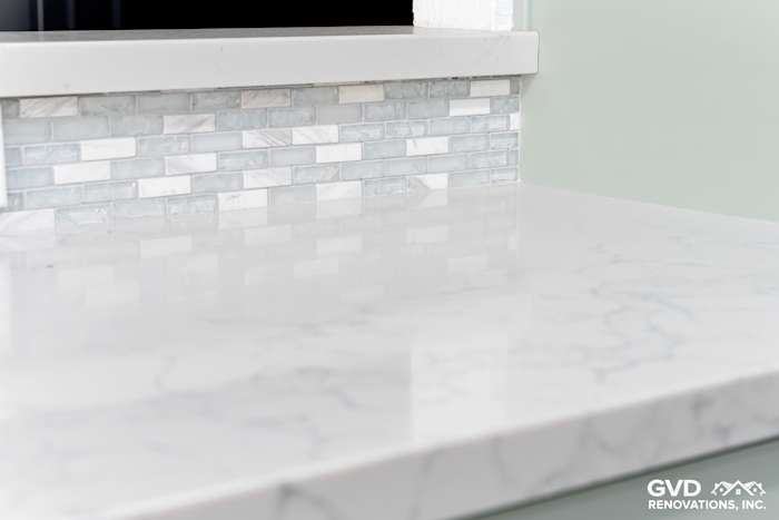 Marble countertop with gray veining, accented by a textured backsplash of light blue and white tiles