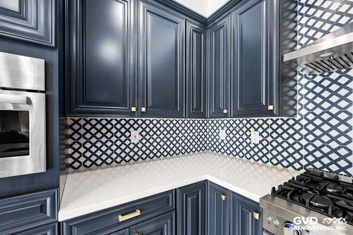 Navy blue cabinets with gold hardware, white quartz countertop, and patterned backsplash in remodeled Sacramento kitchen
