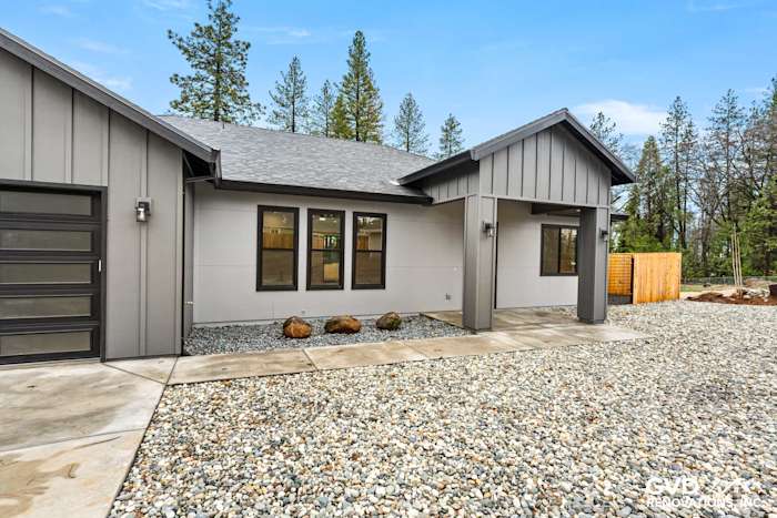 New construction home exterior in Paradise, CA featuring James Hardie panels, Milgard black windows, and gravel landscaping