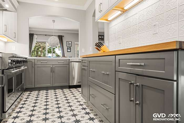 Modern Folsom kitchen remodel featuring gray cabinetry, wood countertops, and patterned black and white tile flooring