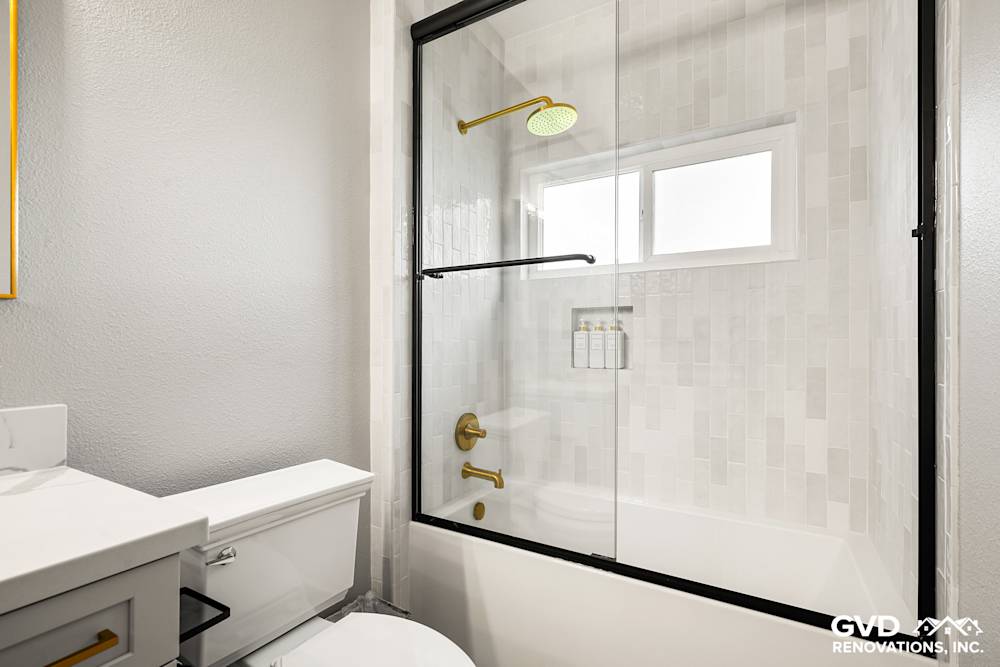 Modern guest bathroom with sliding glass door, matte gold fixtures, and white subway tile accents in El Dorado Hills
