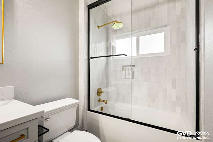 Modern guest bathroom with sliding glass door, matte gold fixtures, and white subway tile accents in El Dorado Hills