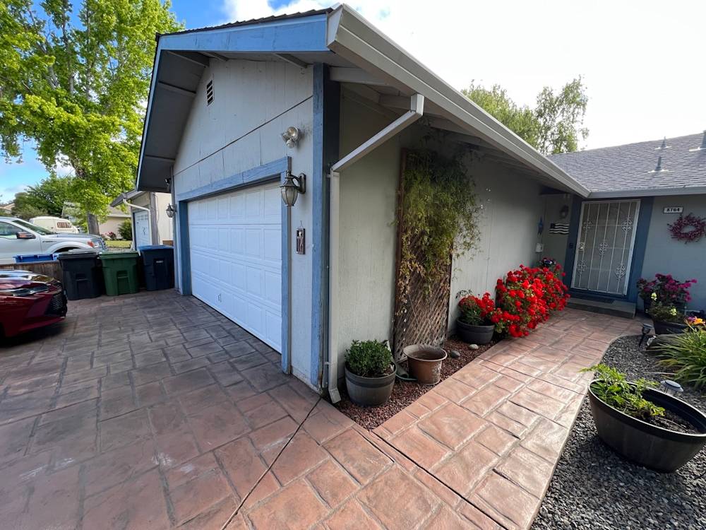 Garage and pathway with stamped concrete, colorful flowers, and greenery in Sacramento