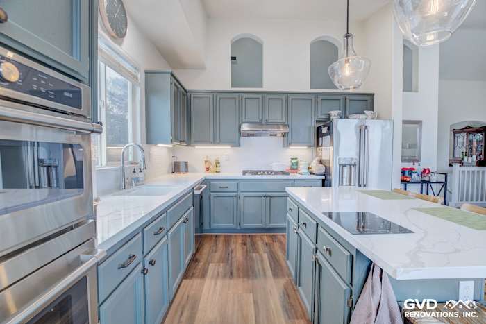 Modern kitchen remodel featuring blue cabinetry, quartz countertops, stainless steel appliances, and natural light in El
