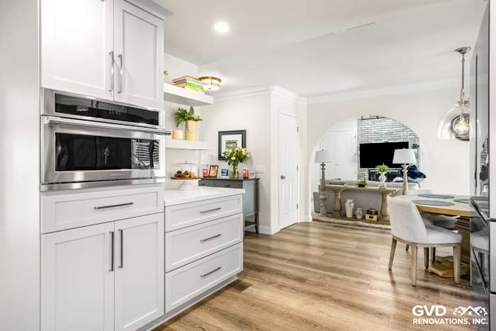 Modern kitchen remodel with white cabinetry, stainless steel appliances, open shelving, and wood flooring in Rocklin