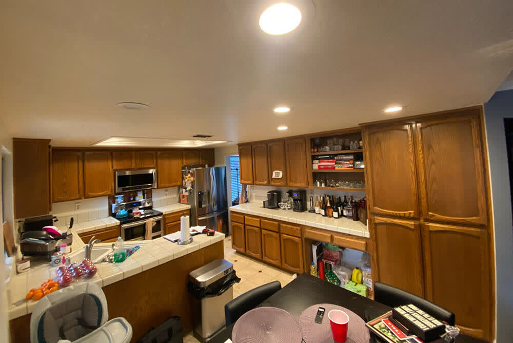 Outdated Sacramento kitchen with wooden cabinets, white countertops, and cluttered countertops