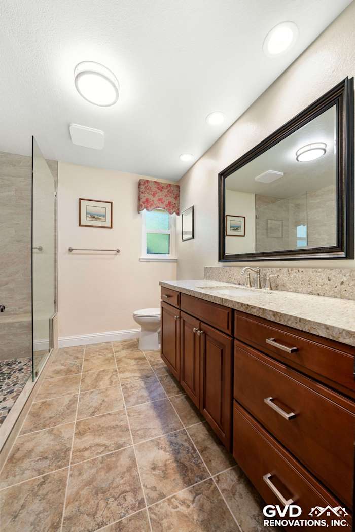Modern bathroom renovation in Fair Oaks featuring granite countertops, dark wood cabinets, and a frameless glass shower