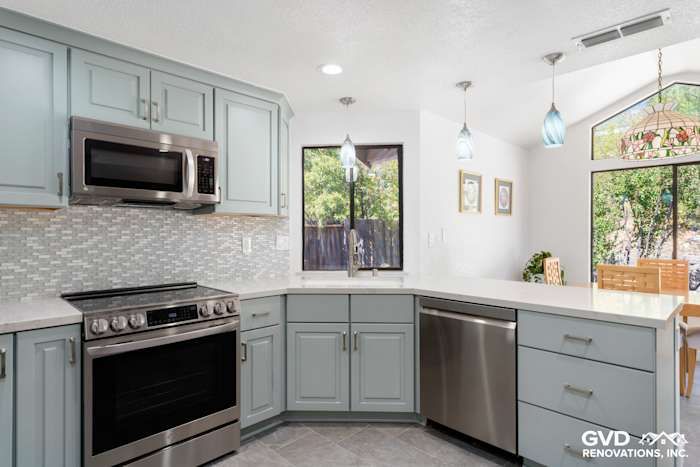 Modern kitchen in Cameron Park featuring light blue cabinets, stainless steel appliances, and glass pendant lighting