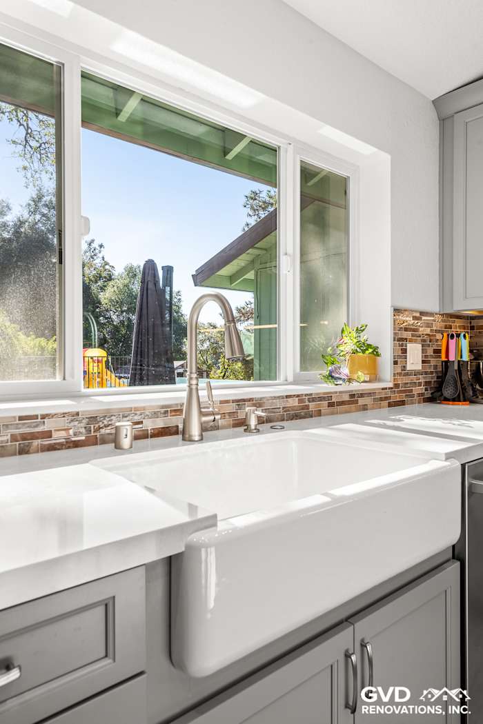 Modern kitchen remodeled with a farmhouse sink, gray cabinets, and a scenic window view in Greenwood, CA