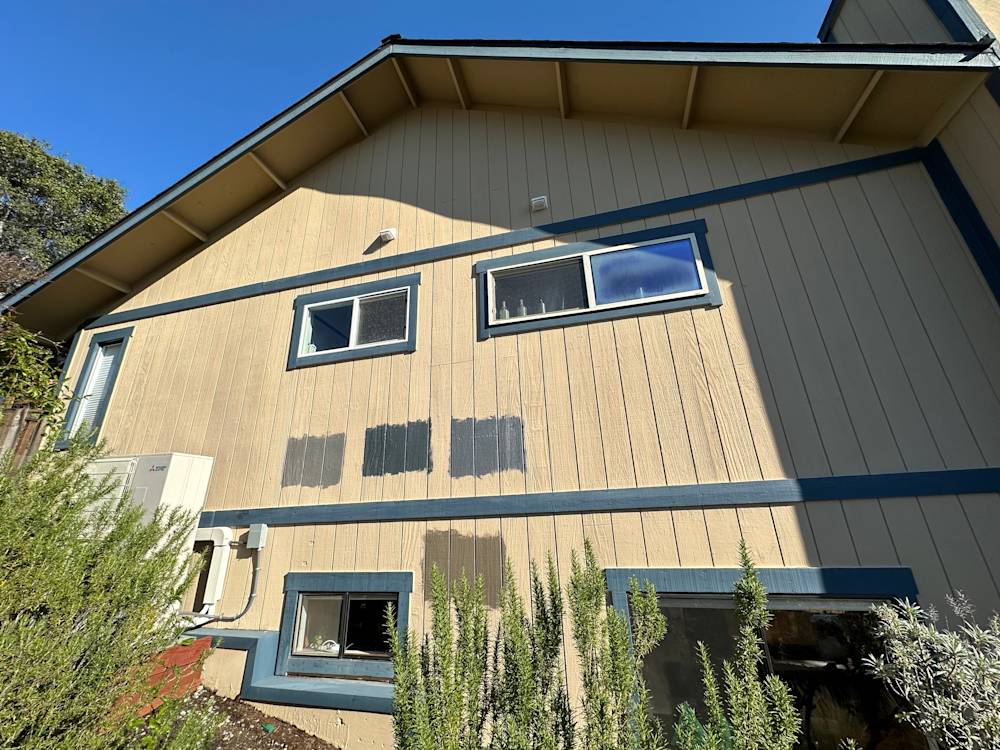 Wooden siding in beige with blue trim, showing patchy paint areas in Sacramento home