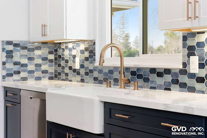 Stylish kitchen with navy and blue hexagon tile backsplash, farmhouse sink, and gold faucet