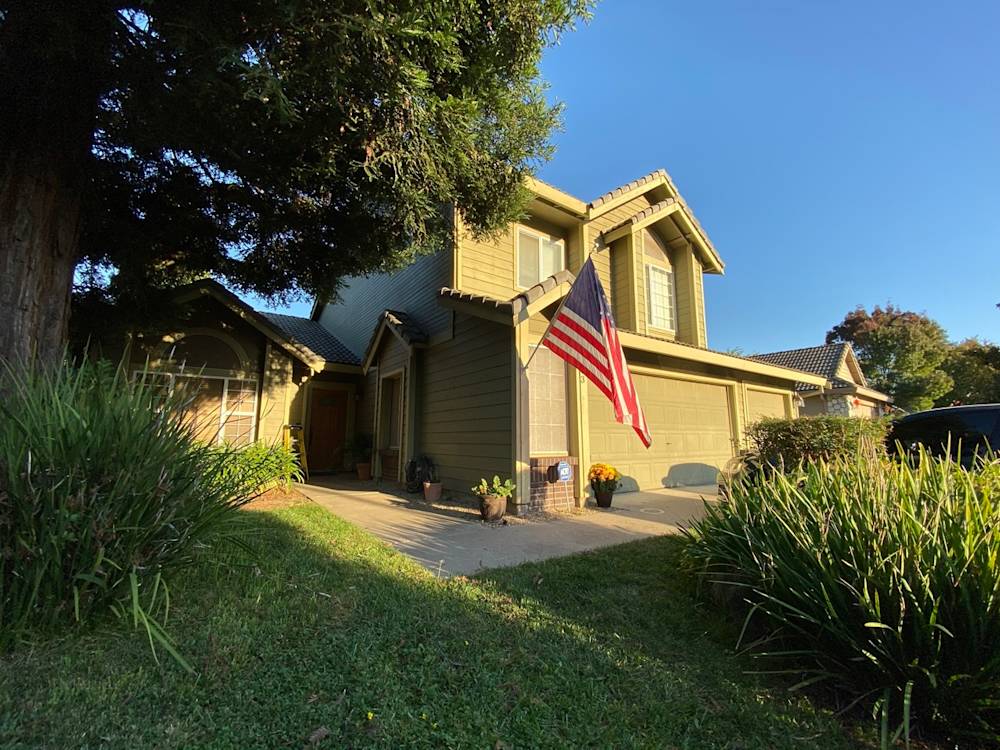 Front yard of home in Sacramento with well-maintained grass, shrubs, and an American flag