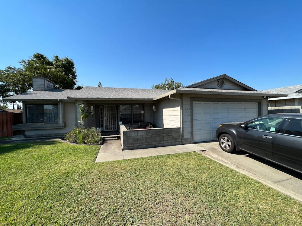 Single-story home in Sacramento with gray siding, manicured lawn, and driveway beside garage