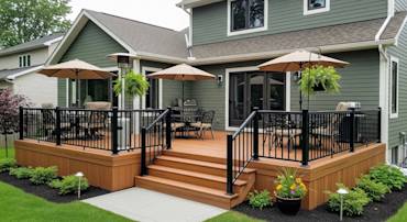 Expansive wooden deck with black railings, seating area, outdoor umbrellas, and lush landscaping in backyard