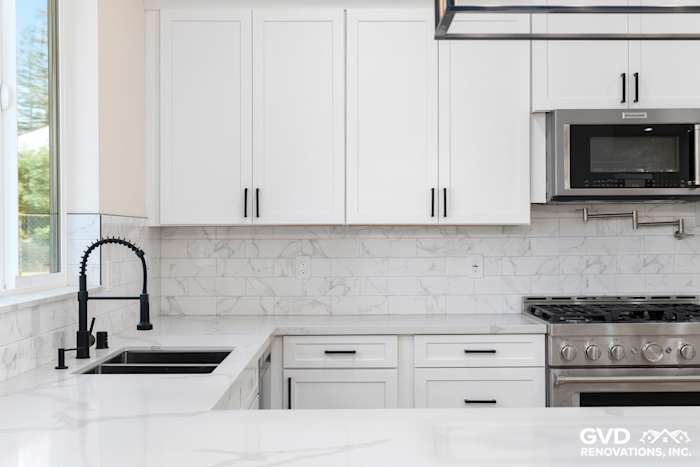 Modern kitchen with white cabinetry, marble backsplash, black faucet, and stainless steel appliances in Paradise, CA