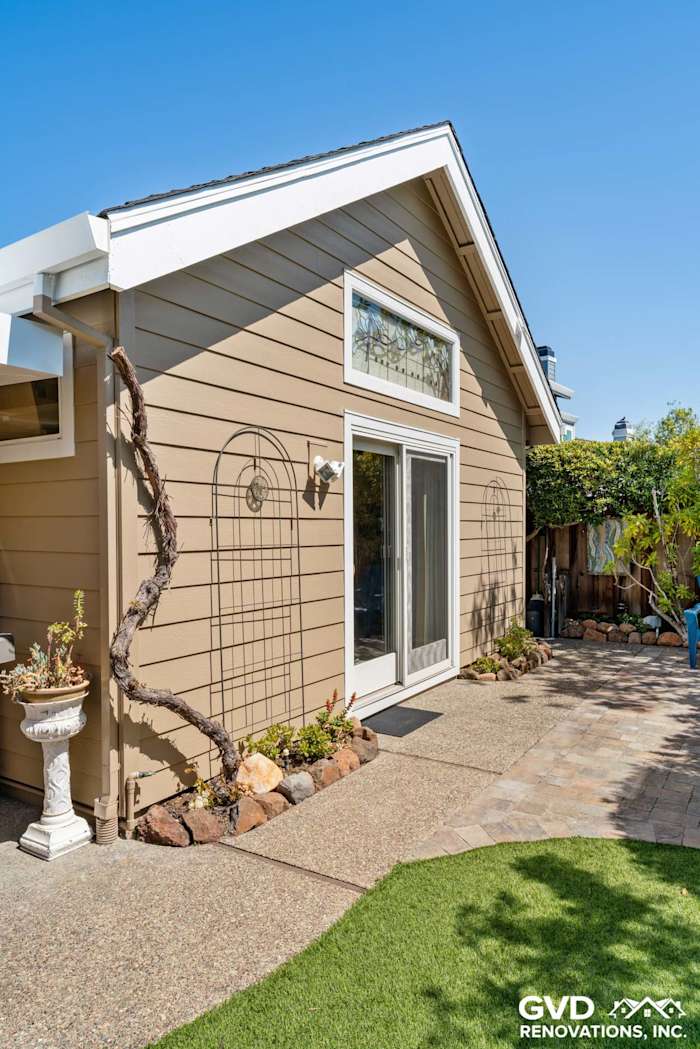 Foster City home exterior with Khaki Brown HardiePlank siding and Arctic White trim, featuring a landscaped patio area