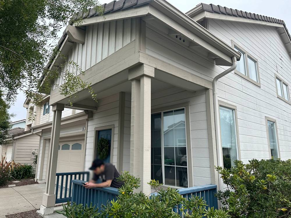 Light-colored wooden exterior with porch, surrounded by shrubs in Sacramento area