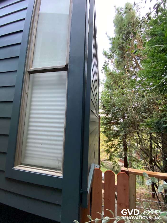 Close-up of newly installed James Hardie siding in dark blue, showcasing corner detail and nearby wooden fence