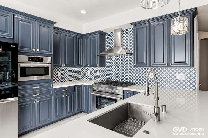 Modern kitchen with navy blue cabinets, white marble countertops, and geometric backsplash in Sacramento remodel