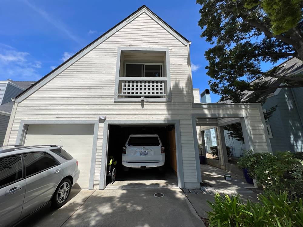 Exterior view of a light-colored wood house in Sacramento with a garage and trees