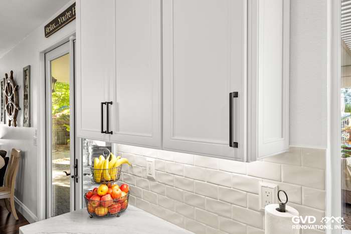 Bright kitchen corner featuring white Fieldstone cabinetry, subway tile backsplash, and fresh fruit basket