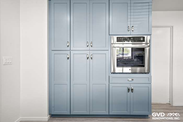 Modern blue Waypoint cabinets with a built-in oven in a remodeled kitchen in Elk Grove