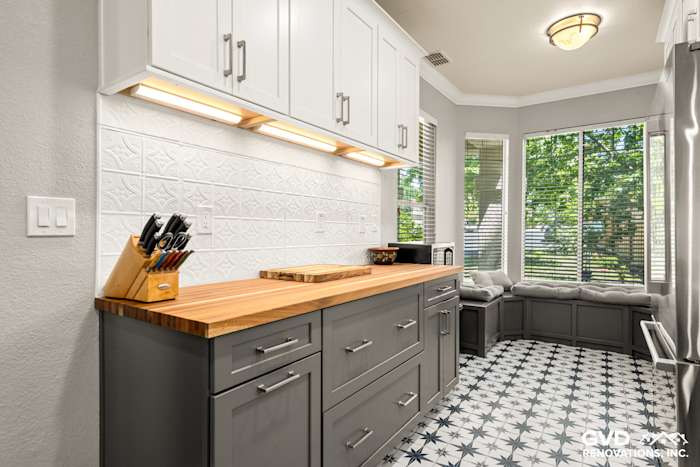 Sleek kitchen remodel featuring gray cabinets, a wooden countertop, and patterned black-and-white floor tiles
