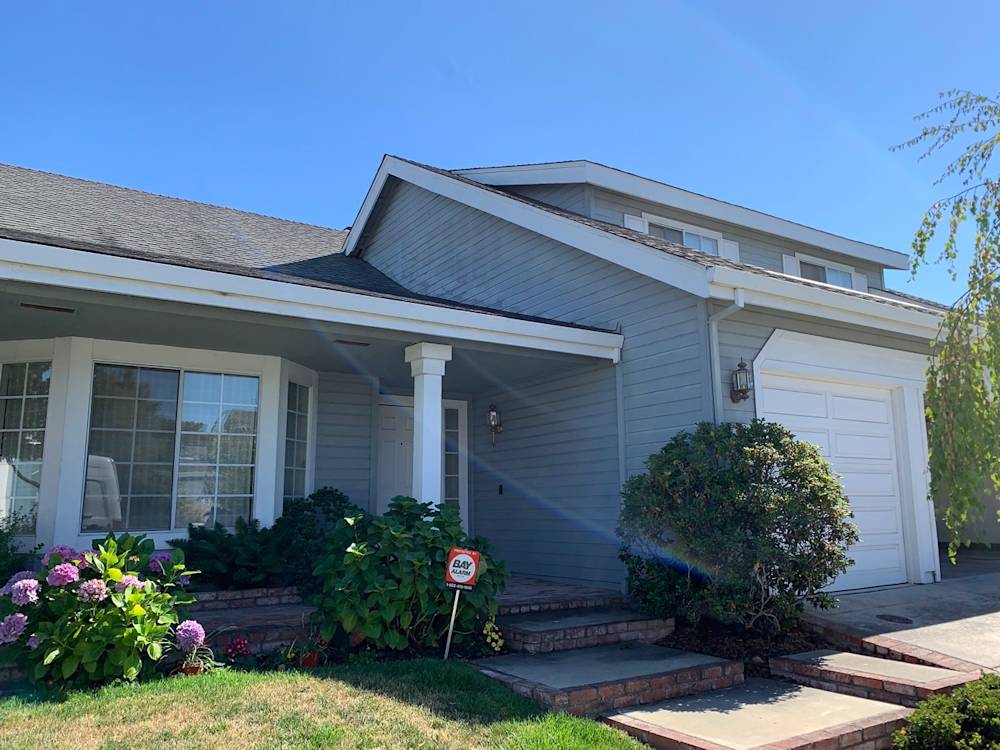 Charming Sacramento home entrance with blue-gray siding, brick steps, and lush green landscaping