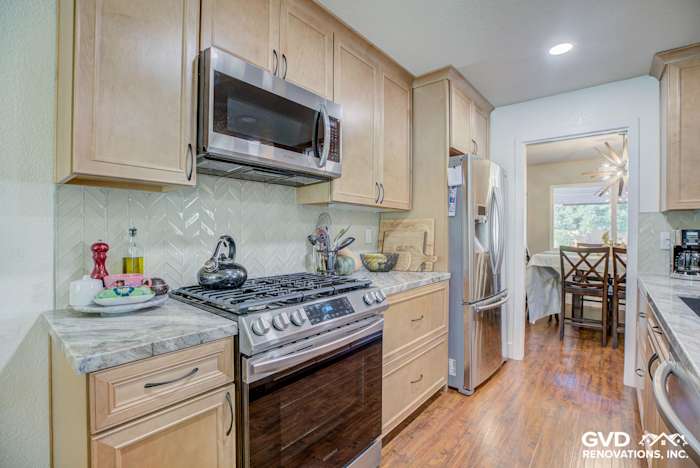 Modern Sacramento kitchen featuring light wood cabinets, herringbone backsplash, stainless steel appliances, and quartz