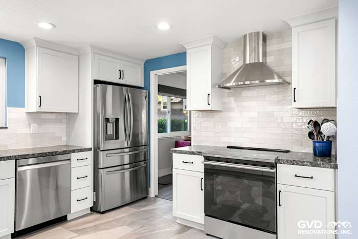 Modern kitchen with stainless steel appliances, white shaker cabinets, gray countertops, and blue accent wall in Fair Oaks