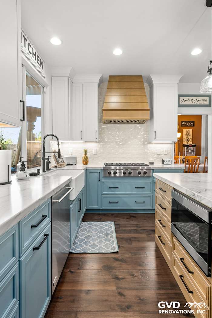 Bright kitchen remodel featuring blue cabinetry, white quartzite countertops, stainless steel appliances, and a wooden range
