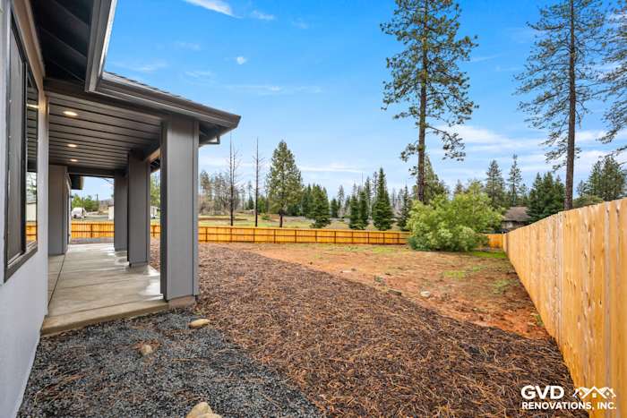 Backyard view of a new construction home in Paradise, featuring a landscaped area with gravel and wooden fence