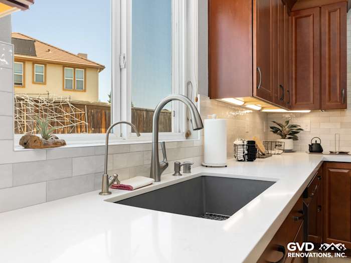 Modern kitchen with a black farmhouse sink, quartz countertop, and warm wood cabinetry in Elk Grove