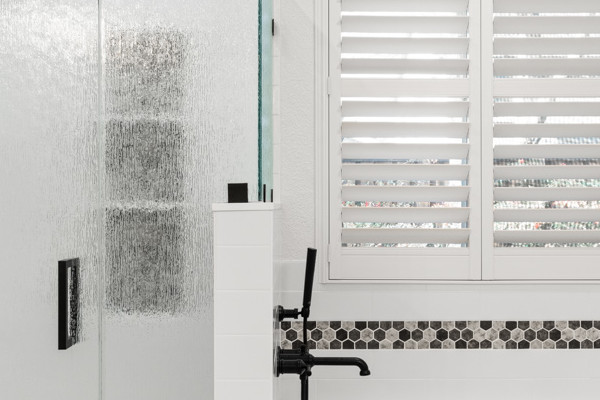 Bright master bathroom featuring a glass shower, soaking tub, modern fixtures, and light-colored finishes
