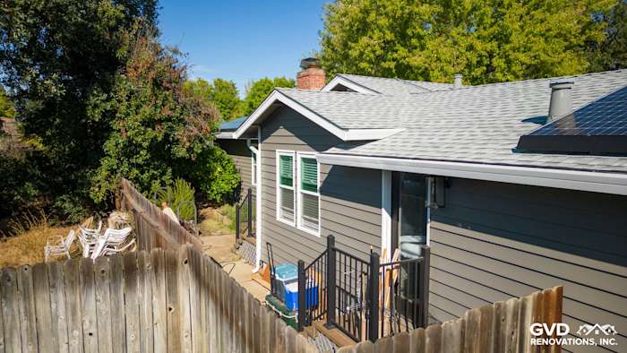 Home exterior with Alside Prodigy vinyl siding in a neutral tone, featuring a new rooftop and rear deck area