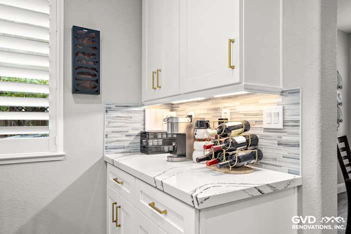 Custom kitchen countertop with Cambria quartz, white cabinets, and stylish wine rack in Roseville remodel