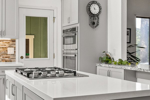 Modern kitchen remodel featuring gray cabinetry, quartz island, and wooden ceiling accents in Greenwood, CA