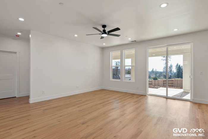 Bright living room in new construction home, featuring smooth walls, large windows, and light wood flooring