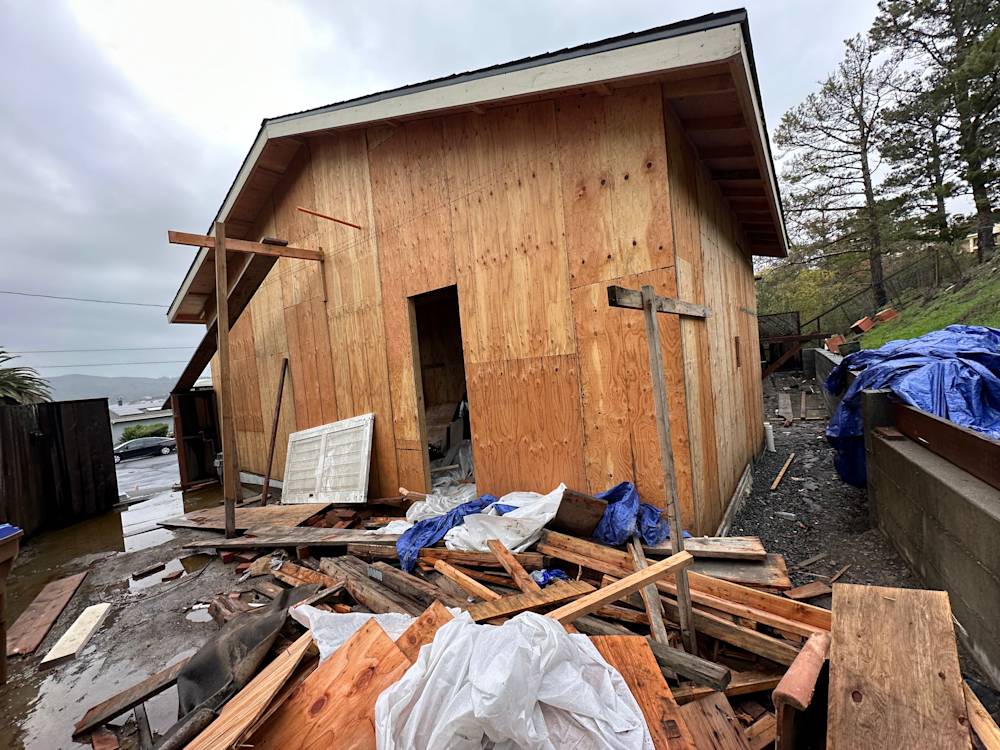 Unfinished exterior of a wooden structure in Tiburon, CA, surrounded by debris and construction materials