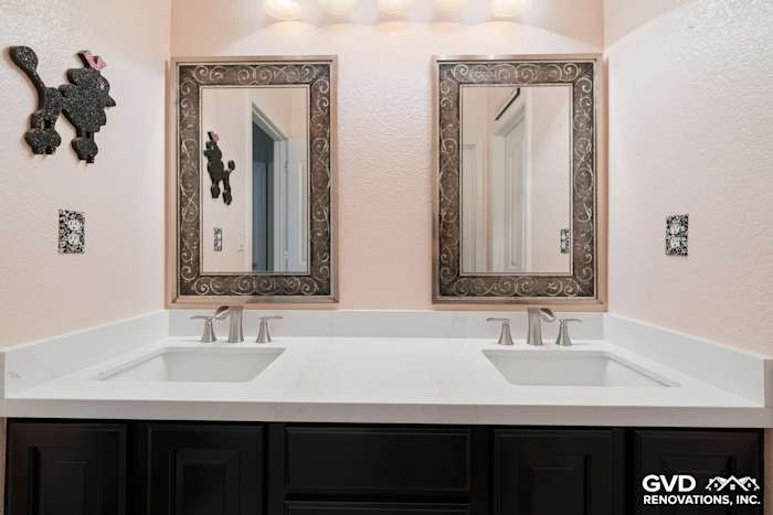 Double vanity with quartz countertop, black cabinetry, and elegant framed mirrors in remodeled bathroom