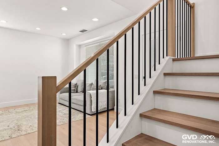 Modern staircase with wood steps and black railings, featuring natural light in an Antelope home remodel