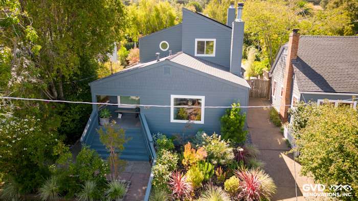 Corte Madera home featuring James Hardie Evening Blue siding and Arctic White trim, surrounded by lush landscaping