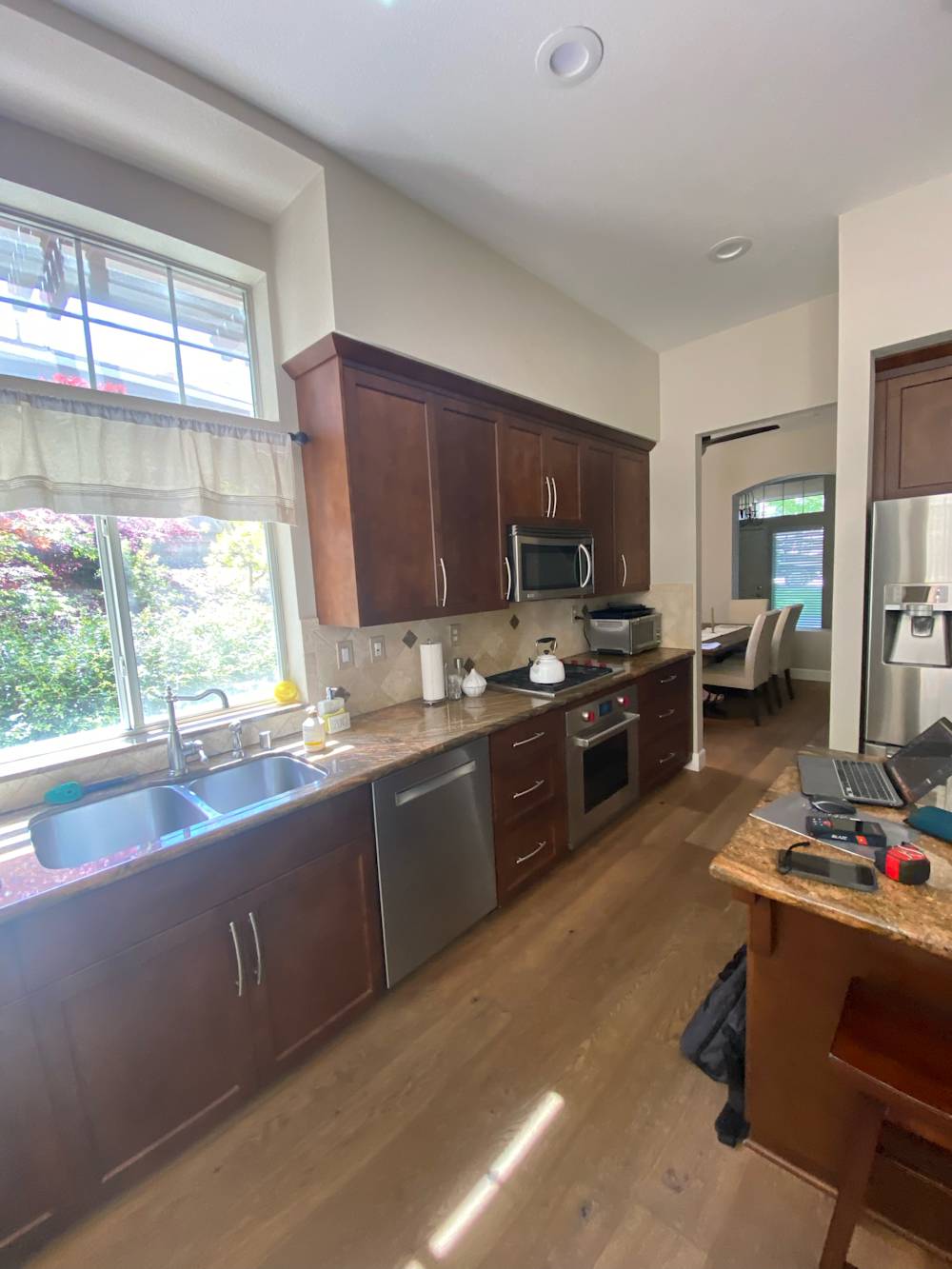 Narrow kitchen with dark wood cabinets, stainless appliances, and a view of greenery outside in Sacramento