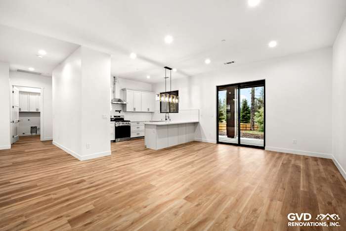Open-concept living area in a new Paradise home featuring hardwood floors, large windows, and modern kitchen design