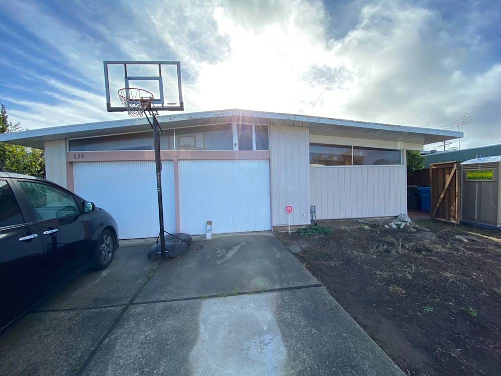 Single-story home exterior in Sacramento with concrete driveway and basketball hoop against a clear sky