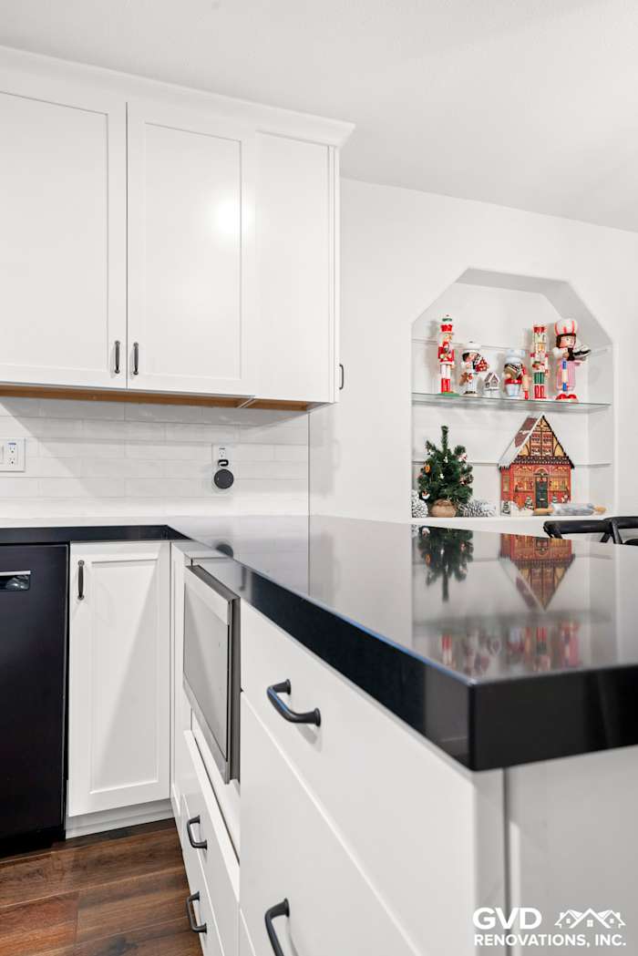 Modern white shaker kitchen featuring black countertops, open shelving, and holiday decor accents