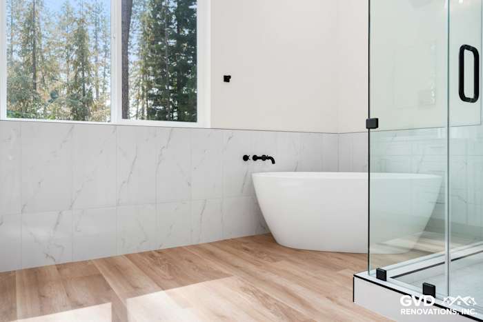 Modern bathroom in Paradise, CA featuring a freestanding tub, marble tile walls, and large glass shower