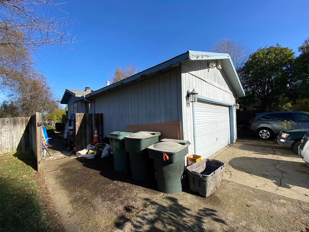 Side view of a Sacramento home featuring a gray exterior and cluttered yard space