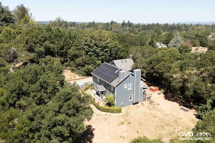 Two-story home featuring new Evening Blue James Hardie lap siding and Arctic White trim, surrounded by trees