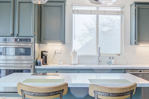 Modern kitchen remodel in El Dorado Hills featuring blue cabinetry, white countertops, and bar seating